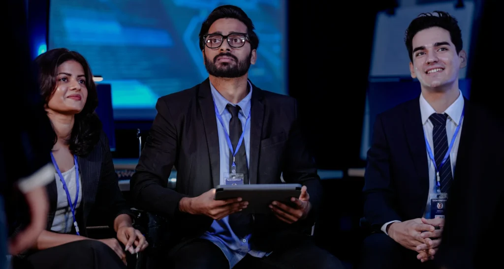 Three business professionals holding tablet at event