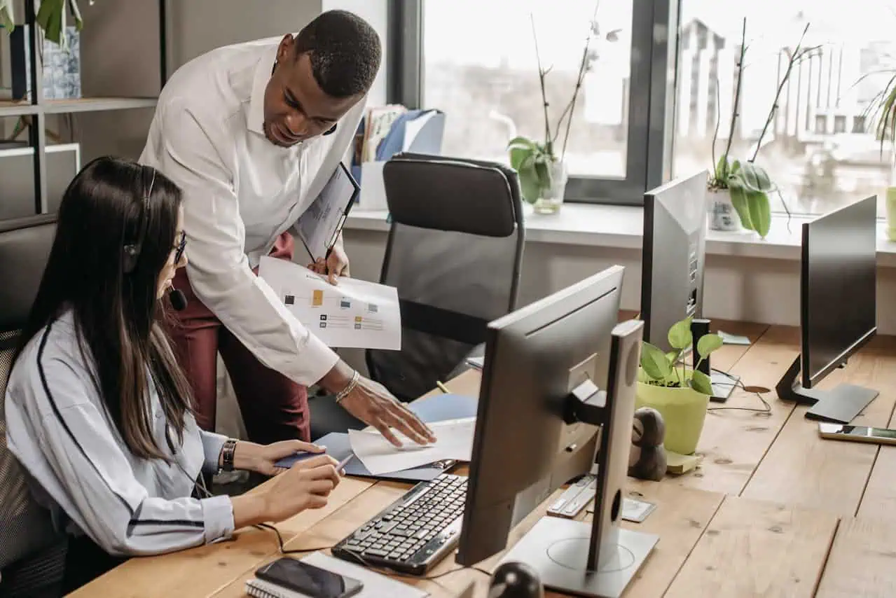 Manager assisting employee with paperwork at office desk
